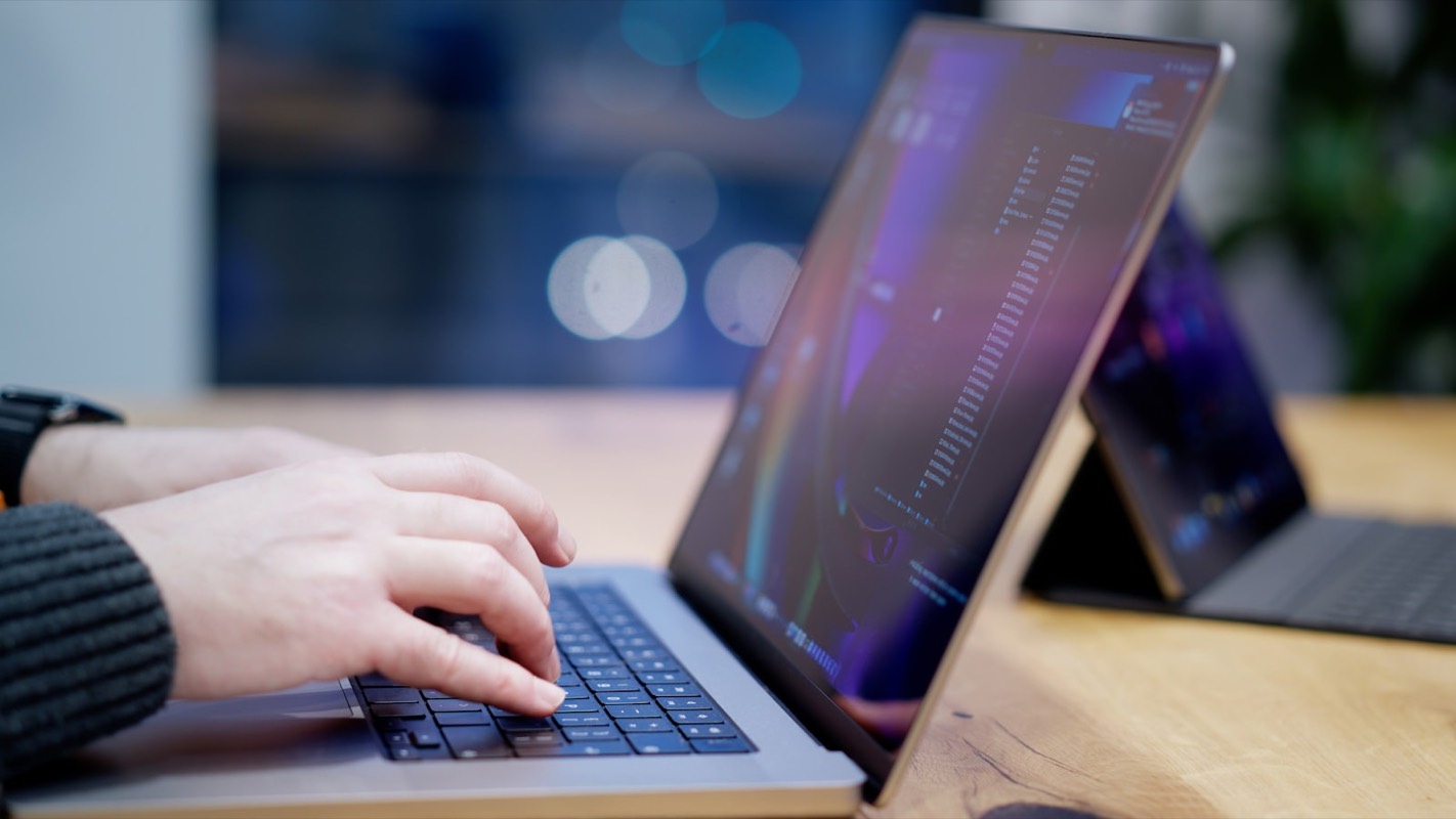 Una persona escribiendo en el teclado de una laptop sobre un escritorio